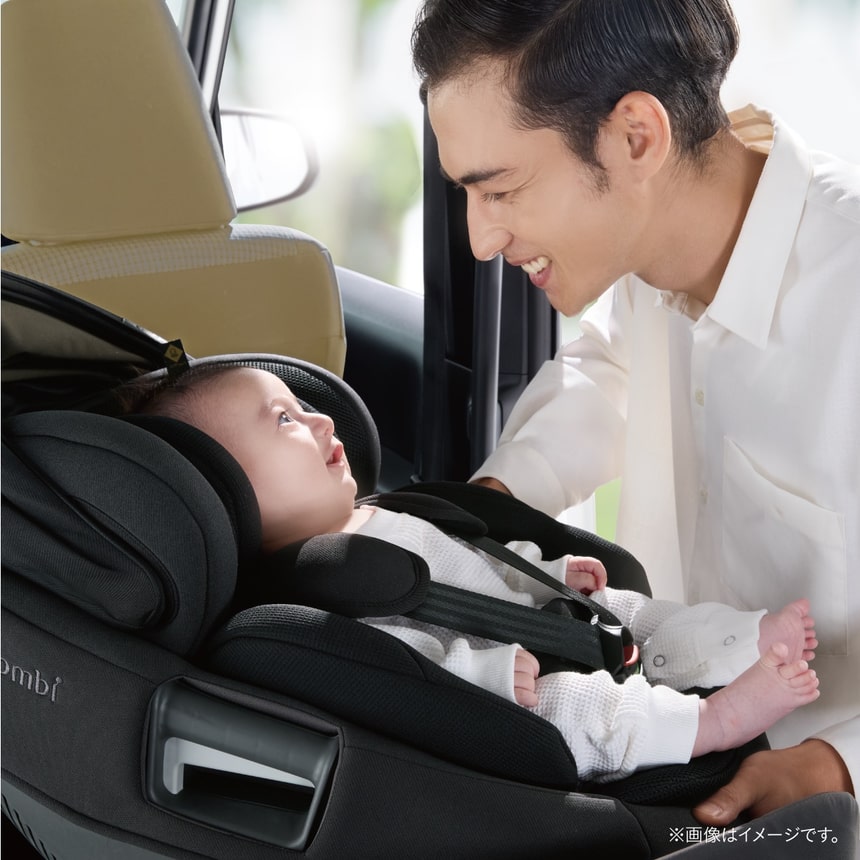 車内でチャイルドシートに座る赤ちゃんを笑顔で見守るお父さん