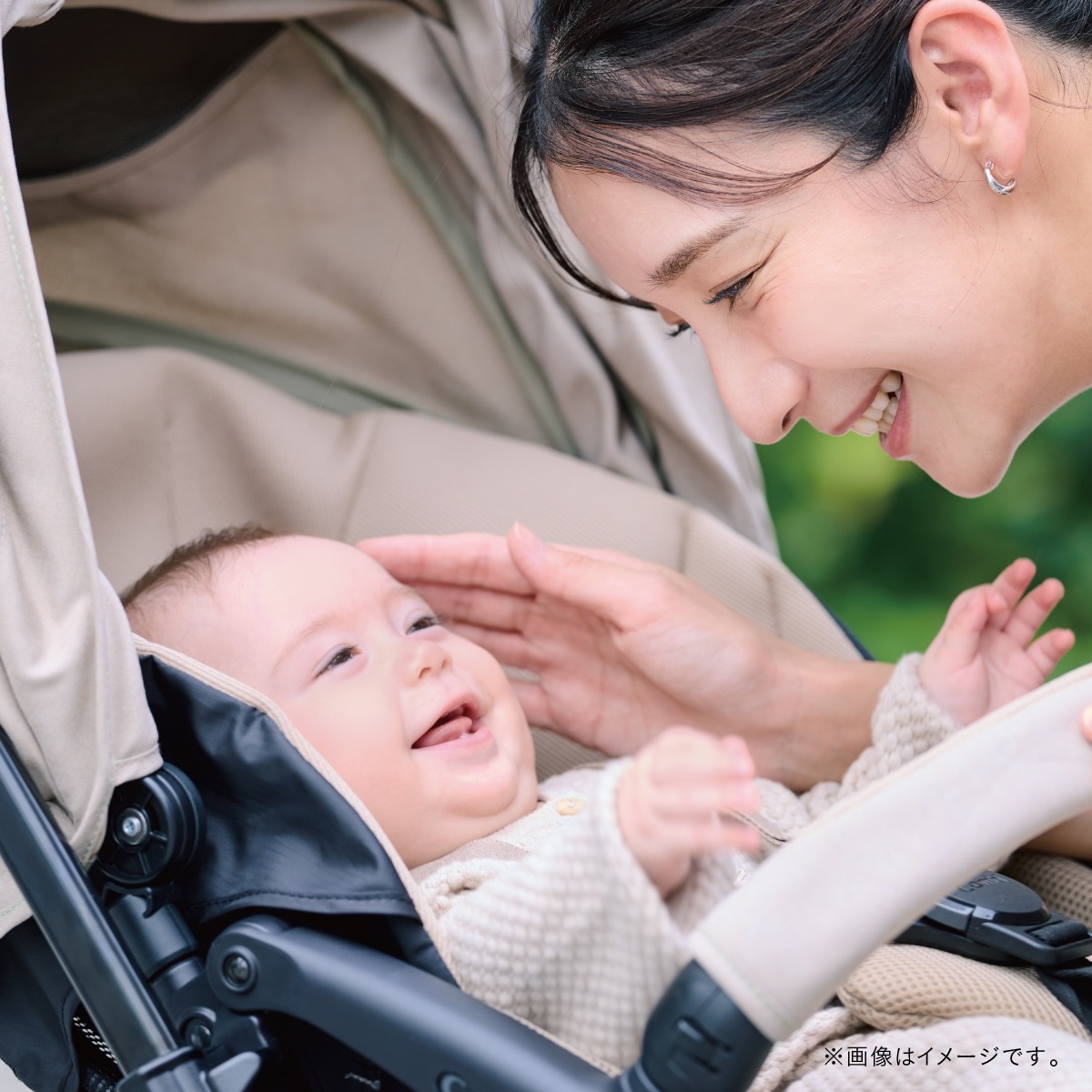 コンビの軽量ベビーカー「スゴカル」に乗った赤ちゃんと、笑顔で見つめ合うママ。赤ちゃんはやわらかなシートに包まれながら、ママに手を伸ばしてにっこり。親子のふれあいと、ベビーカーでのお出かけの心地よさを表現したイメージ。